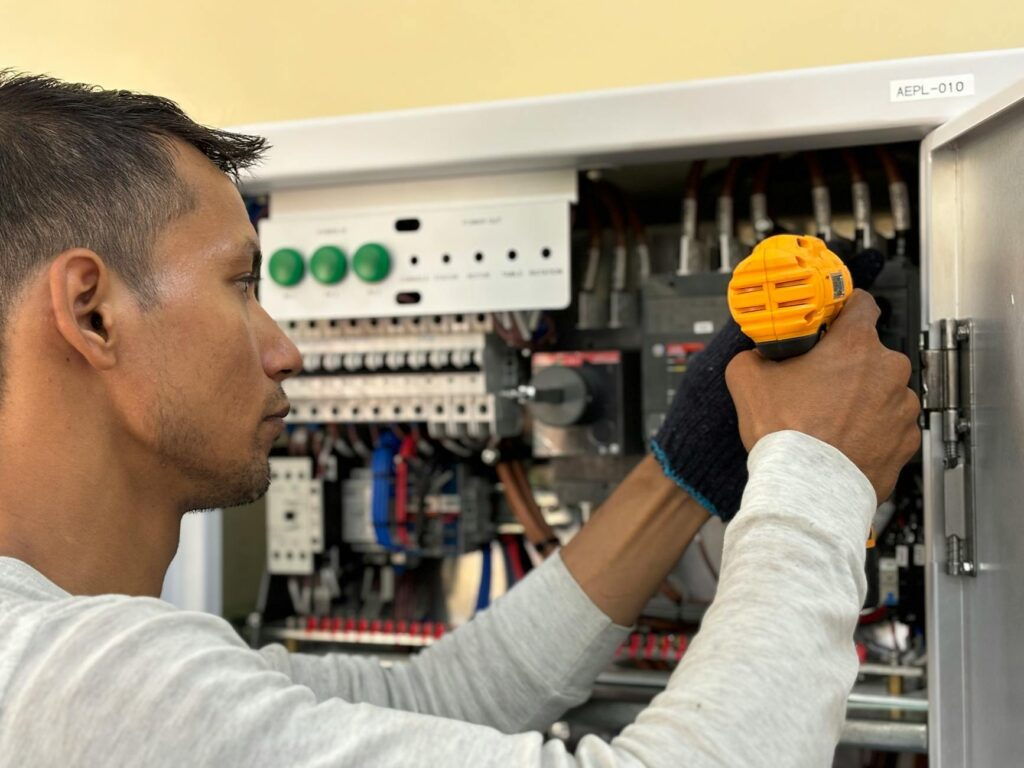 electrician reviewing certification documents beside electrical panel